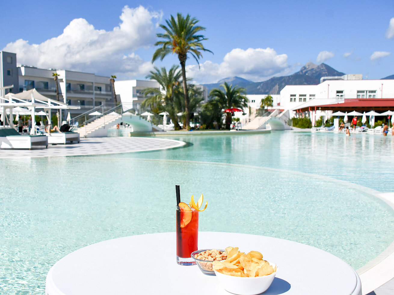 Snacks und ein Cocktail am Lagunenpool des Maritim Resort Calabria. Perfekte Auszeit mit Blick auf die Berge.