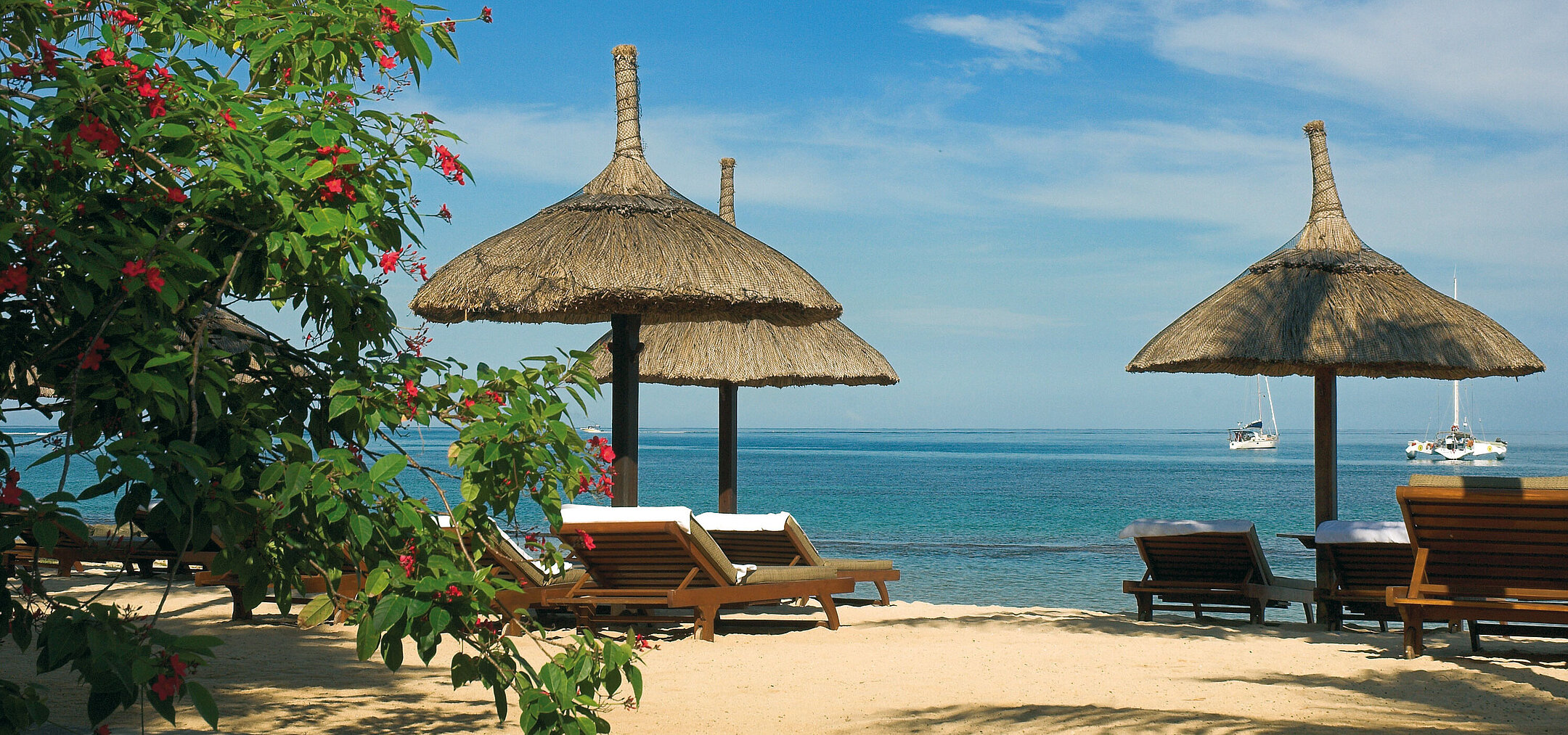 Sonnenliegen unter Strohschirmen mit Meerblick im Maritim Hotel Mauritius