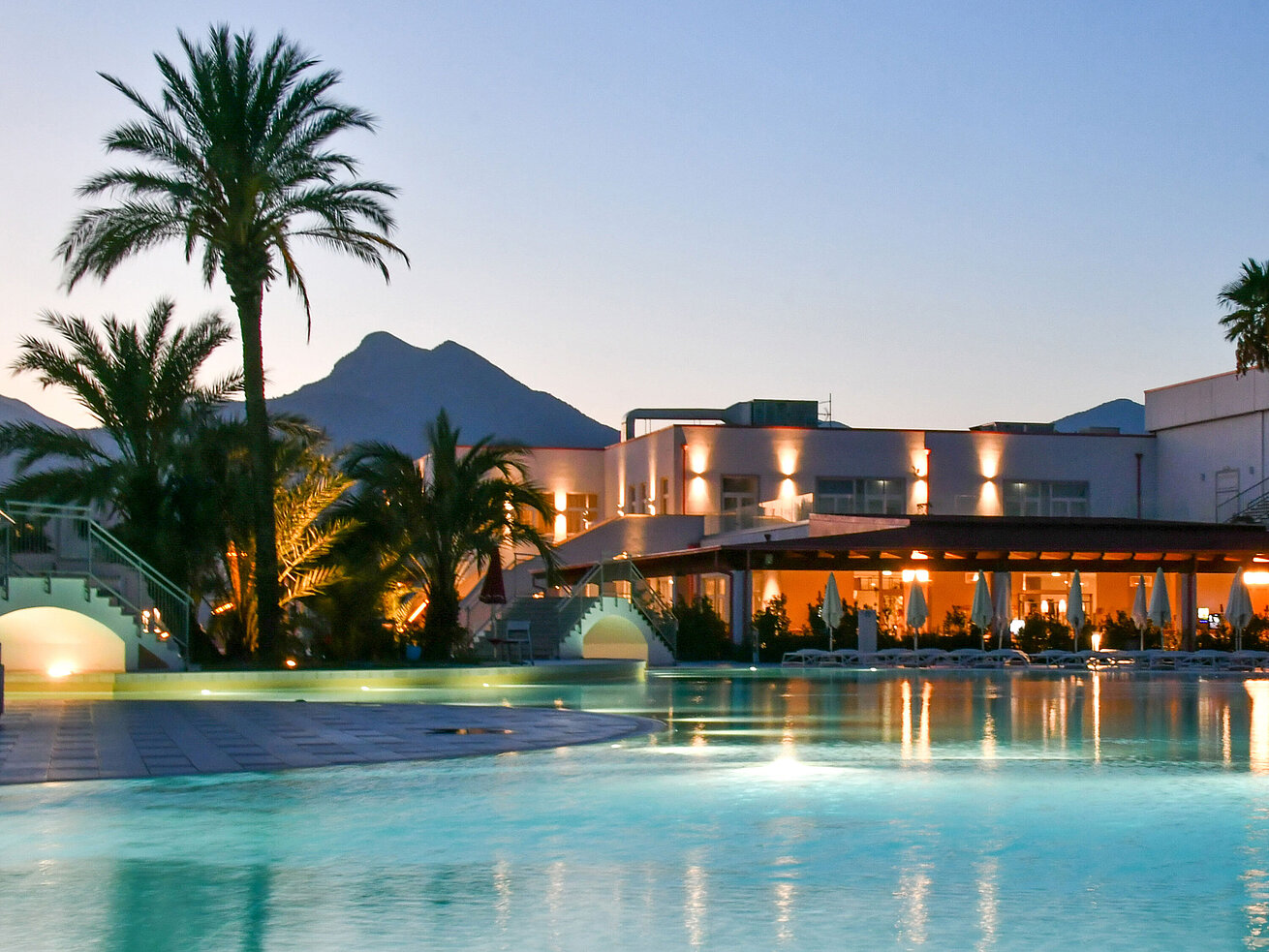 Poolbeleuchtung am Abend im Maritim Resort Calabria mit Palmen und Gebirgskulisse